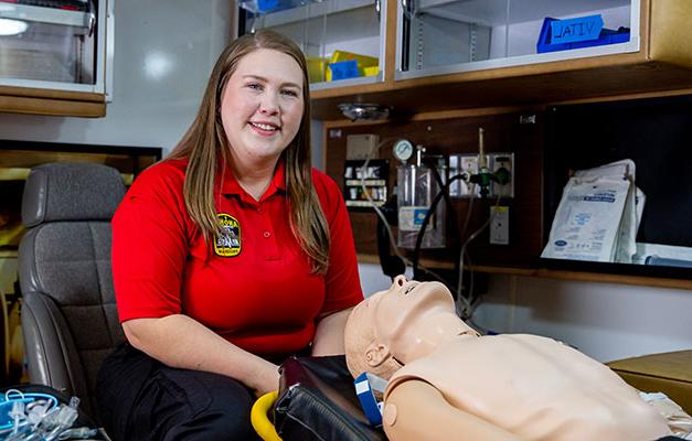 paramedic student in red polo uniform shirt in ems lab